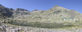 Un paisaje montañoso con un lago de aguas tranquilas y rocas circundantes en la Sierra de Gredos.