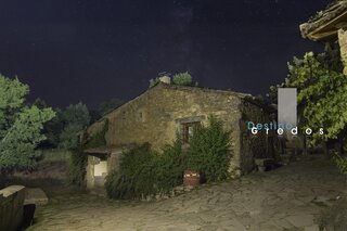 Una casa de piedra con un cartel de destino en un camino de tierra en la Sierra de Gredos.