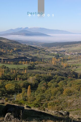 Una imagen de un paisaje rural con un terreno montañoso y vegetación, posiblemente en otoño en la Sierra de Gredos.