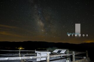 Una imagen de un paisaje nocturno con un cielo estrellado y una estructura de madera en primer plano en la Sierra de Gredos.