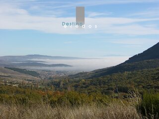 Una vista panorámica de un pueblo en un valle, con niebla en la distancia y montañas en el fondo en la Sierra de Gredos.