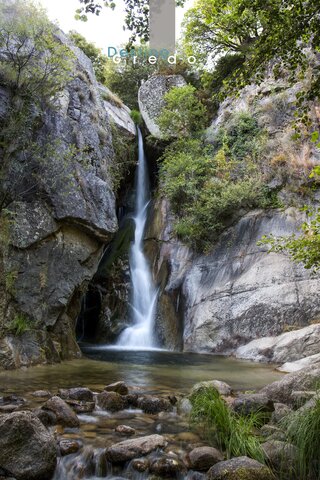 Una cascada en un entorno rocoso con agua fluyendo sobre piedras en la Sierra de Gredos.