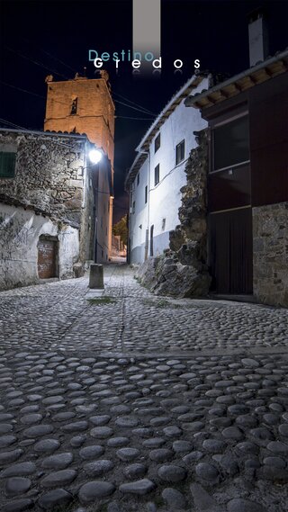 Una calle empedrada en un pueblo, con edificios de piedra a ambos lados en la Sierra de Gredos.
