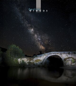 Una imagen nocturna de un puente sobre un cuerpo de agua, con un cielo estrellado en la Sierra de Gredos.