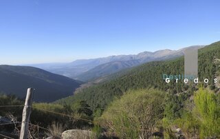 Una imagen de un paisaje montañoso con vegetación y un valla en la Sierra de Gredos.